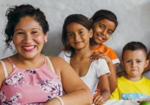 One woman and three children smiling.