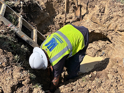 Crew worker digging in hole.