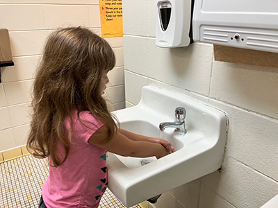 Little girl washing her hands at school